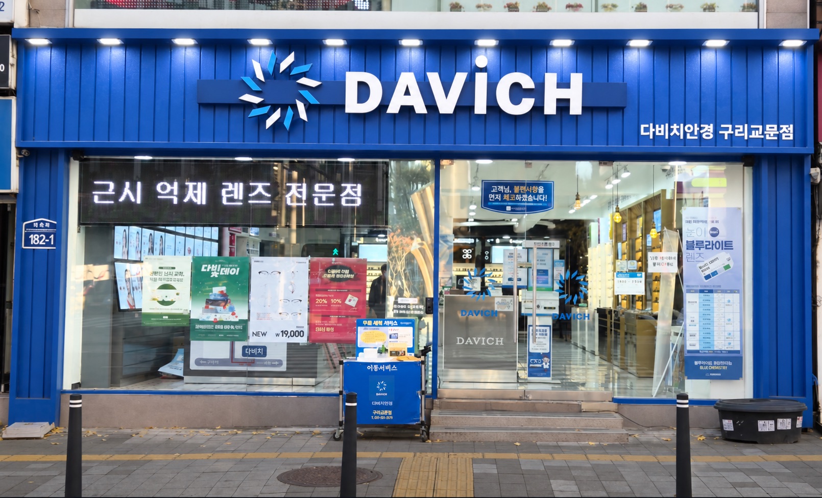 다비치안경 구리교문점 외관 — 파란 간판에 조명이 켜진 저녁 전경